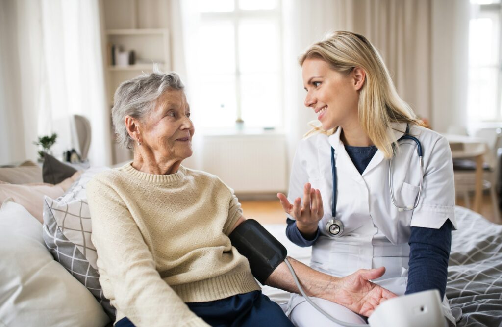 A health visitor measuring a blood pressure of a senior woman at home.