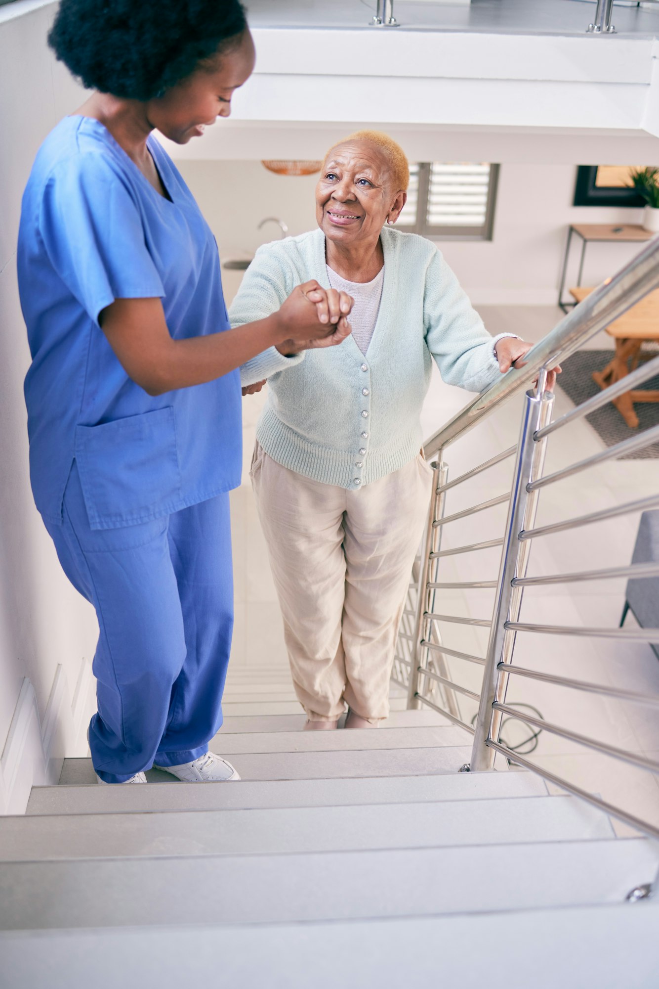 Caregiver, stairs and elderly woman holding hands, help and assistance in home. Nurse, steps and se