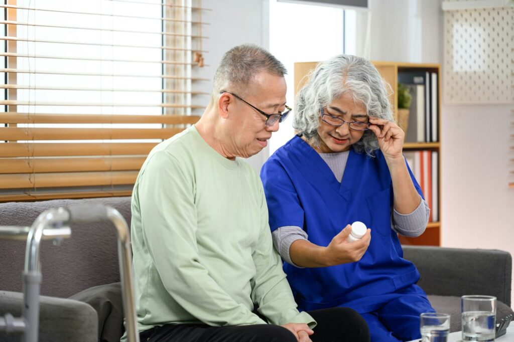 Female doctor explaining medicine dosage to senior patient at home. Healthcare concept