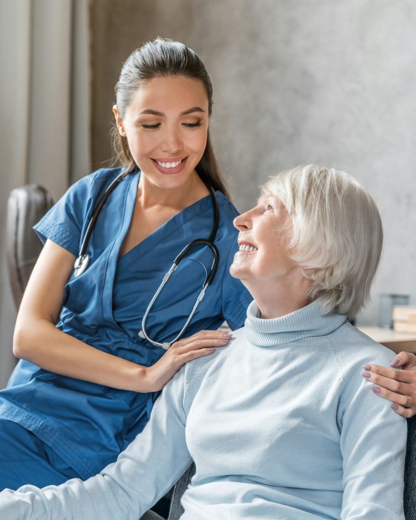 Vertical portrait of happy elderly woman with nurse at home